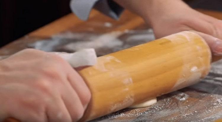 We roll out a thin circle of dough with a rolling pin.