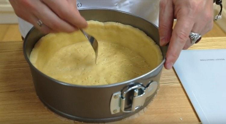 We prick the bottom and sides of the future cheesecake with a fork.