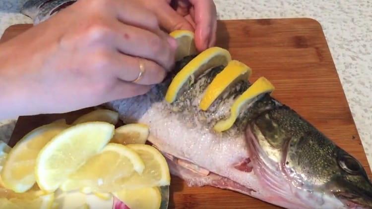 Dans les incisions faites sur le brochet avec un couteau, insérer des tranches de citron.