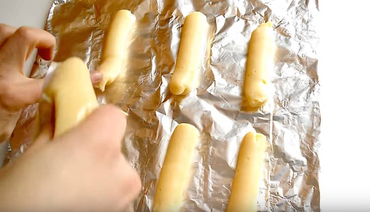 Los eclairs largos se plantan en una bandeja para hornear cubierta con pergamino o papel de aluminio.