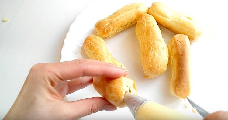 Using a pastry bag with a nozzle, fill the eclairs with cream.