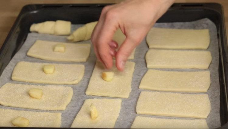 On the center of each piece of dough, lay out a piece of apple.