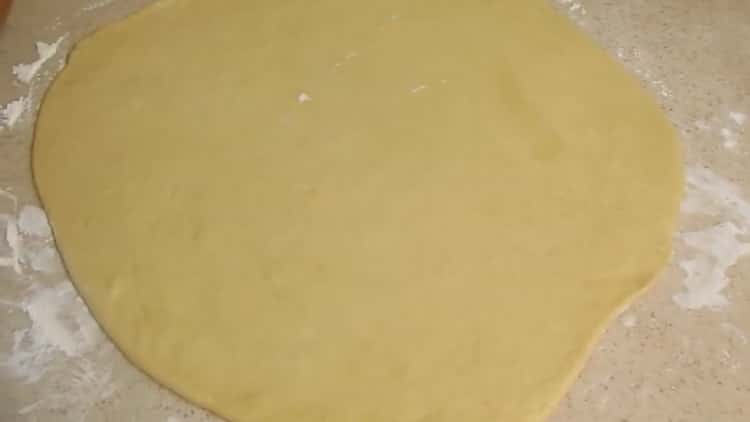 Rouler la pâte pour faire des brioches à la cannelle et du beurre