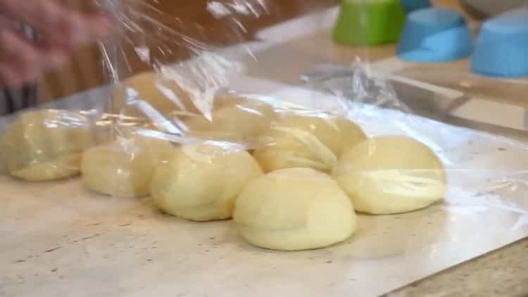 Para hacer bollos de hamburguesa, coloca la masa debajo de la película