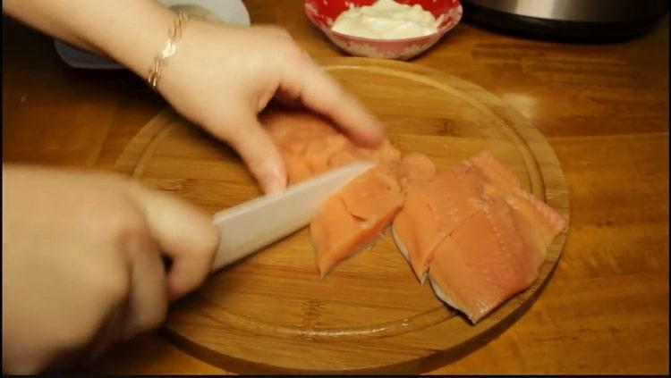 Para cocinar salmón rosado en una olla de cocción lenta, corte el pescado.
