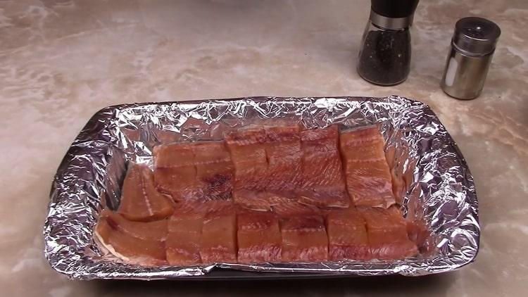 Pour préparer le saumon rose dans une sauce crémeuse, mettez le poisson dans une plaque à pâtisserie