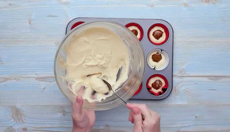 Da biste pripremili cupcakes sa kondenziranim mlijekom, stavite tijesto na vrh kondenziranog mlijeka
