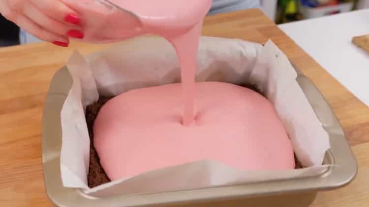 To prepare a strawberry cheesecake, pour the cream onto the base