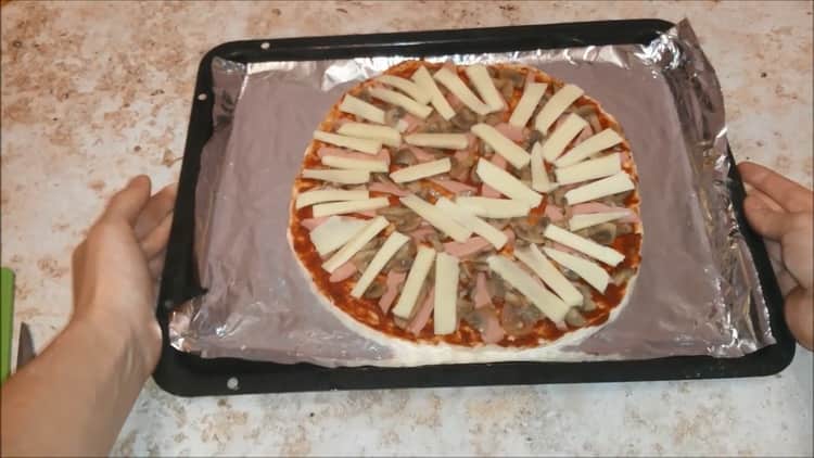 Para cocinar pizza con salchichas y queso, precaliente el horno