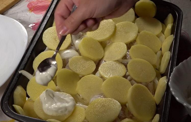 Za kuhanje bakalara s krumpirom u pećnici, namažite krumpir kiselim vrhnjem