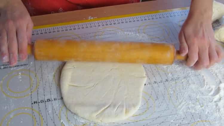 Rouler un gâteau pour faire du khachapuri avec du fromage cottage et du fromage