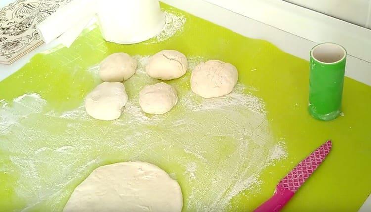 Each ball of dough is portionwise rolled into a cake.