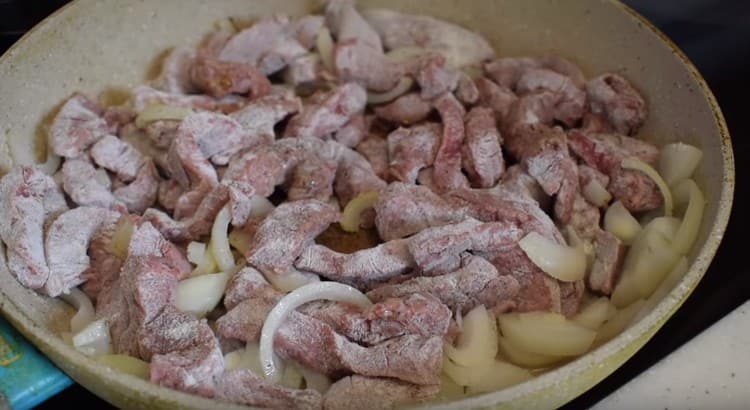 Nous répartissons le bœuf dans la farine dans une casserole jusqu'à l'oignon et nous le faisons frire jusqu'à ce qu'il soit doré.