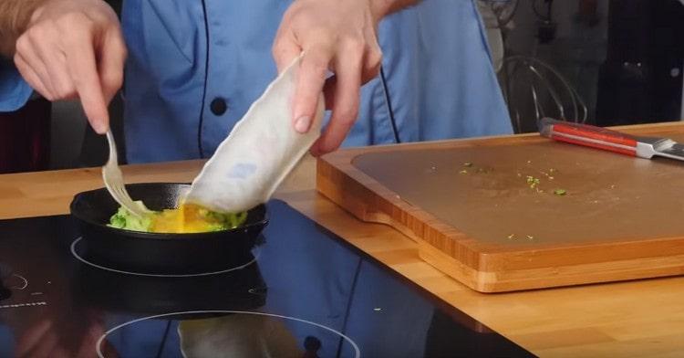 Ponga los pedazos de brócoli en una sartén, llénelos con huevo y cocine debajo de la tapa.