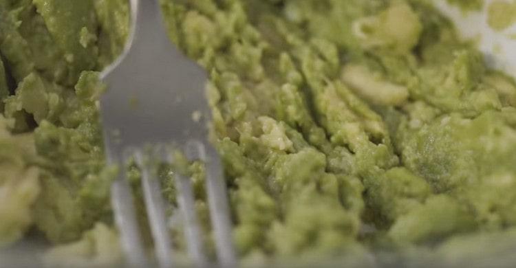 Knead the pulp of mashed avocado with a fork.