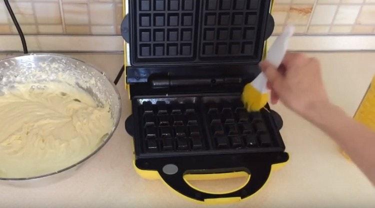 We heat the electric waffle iron, grease the forms with vegetable oil.