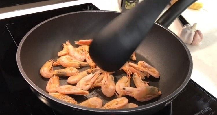 Répartir les crevettes dans une poêle sèche chauffée.
