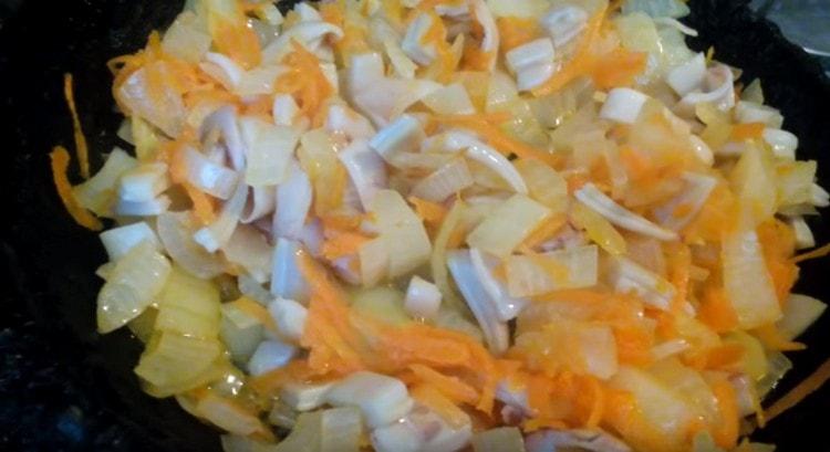 Fry onions with carrots and squid slices in a pan.