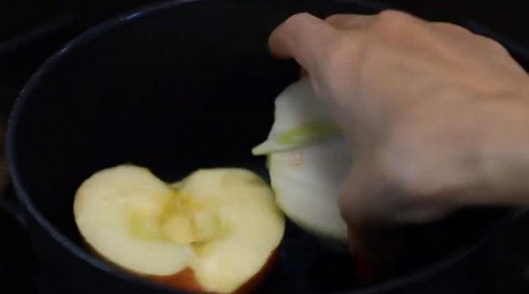 Dans une casserole, étendre une demi-pomme et un demi-oignon.