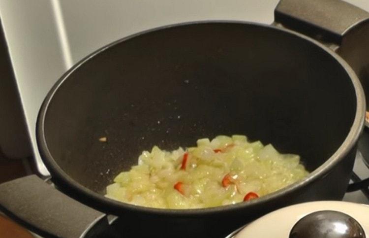 In a cauldron, add chili pepper to the onion.
