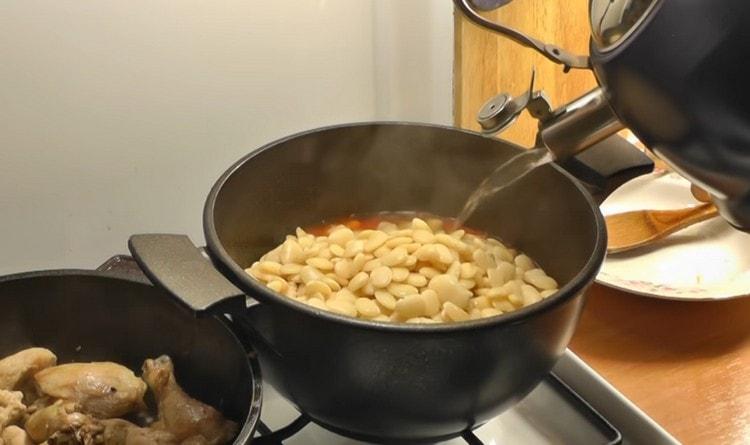 We transfer the boiled beans to tomato sauce, add water.