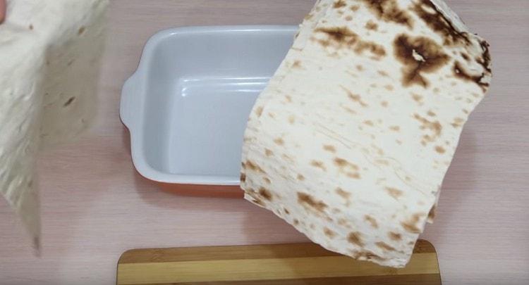 Pita bread is cut into pieces corresponding to the size of the baking dish.