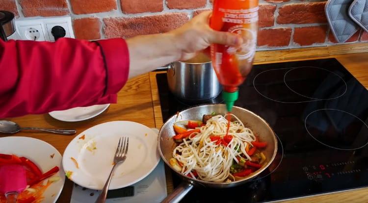 Put the noodles in the pan, add soy sauce and sriracha sauce.