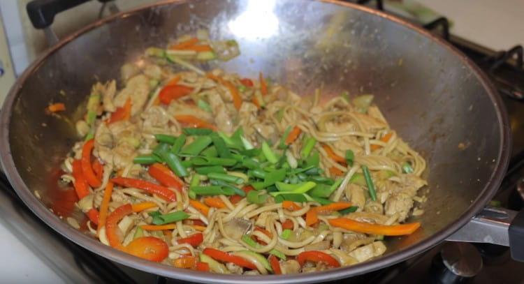 Mélangez udon avec du poulet et des légumes, ajoutez des oignons verts.