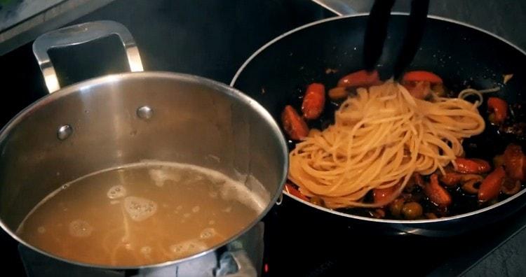 We shift almost ready spaghetti into the pan.