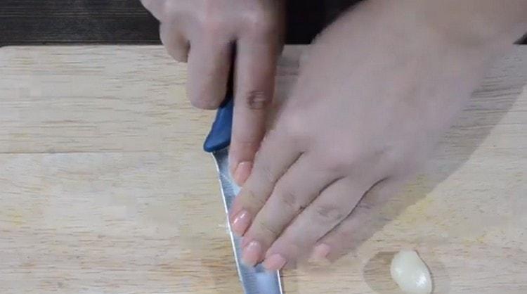 Crush the garlic with the flat side of the knife.