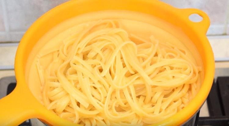 Les spaghettis s'inclinent dans une passoire.