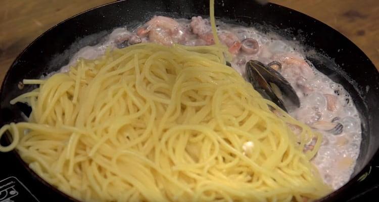 tiramos la pasta en un colador y la transferimos a una sartén de mariscos.