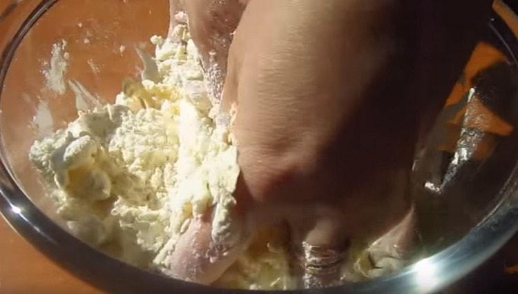 Hands grind flour and butter into crumbs.