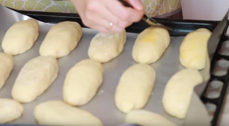 Extendimos los pasteles formados en una bandeja para hornear cubierta con pergamino y grasa con un huevo batido.