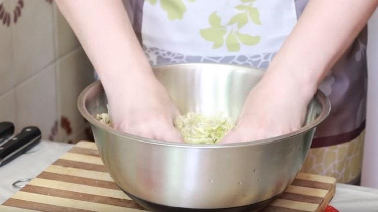 Hands crush cabbage, adding a little salt.