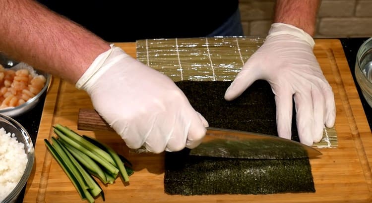 We spread the sheet of nori on the mat, cut off the excess edge.