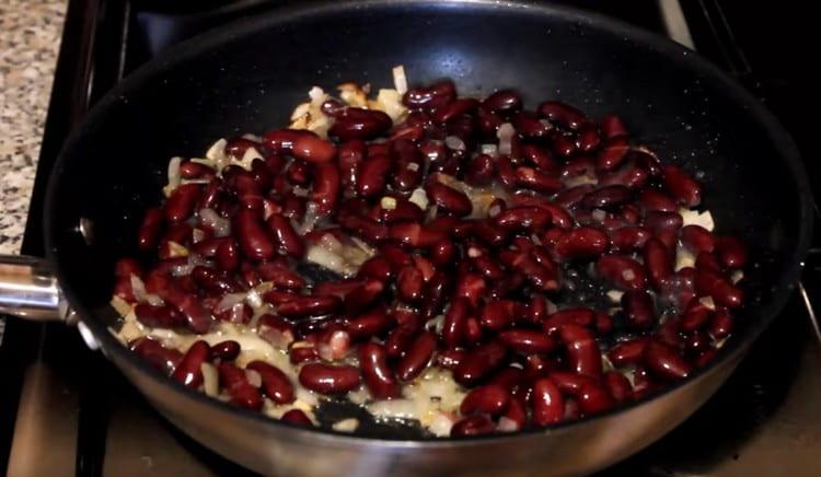Add canned beans to the onion, mix.