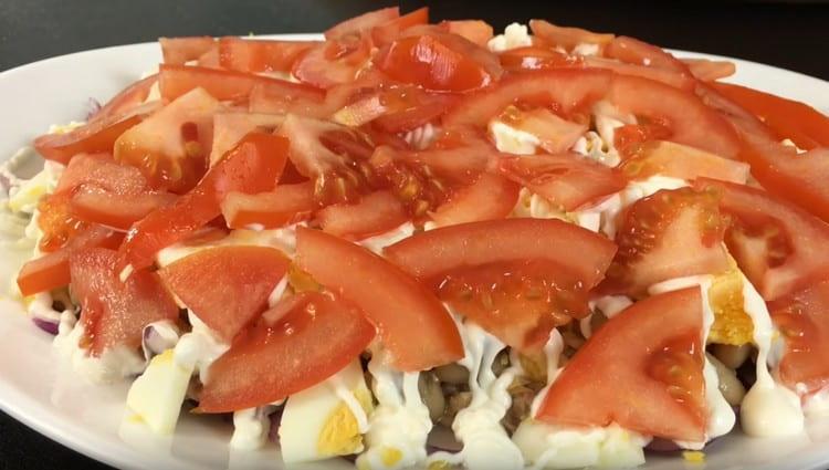 Cut the tomatoes into slices and spread them in the next layer of salad.