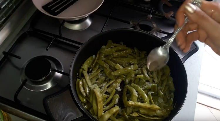 Beans are added to the pan to the onion, salt and pepper the dish.