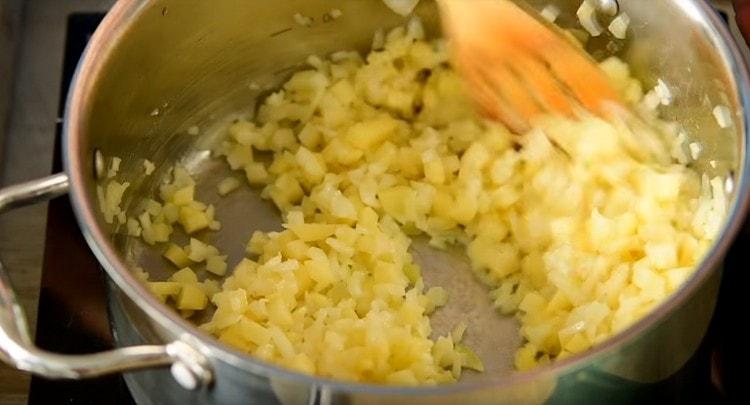 guisar cebollas y papas en mantequilla en una sartén con un fondo grueso.