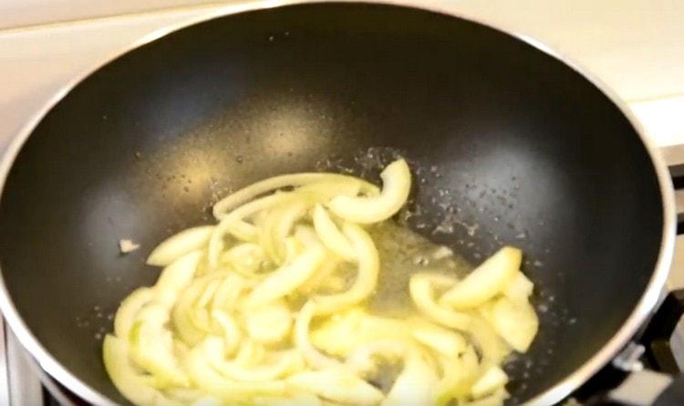Pržite luk narezan na pola prstena u maslacu i biljnom ulju.