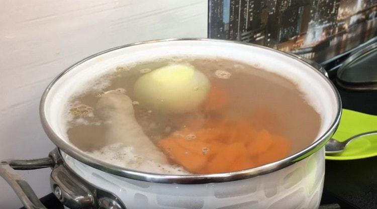 Dans un bouillon bouilli, étalez les carottes et un oignon entier pelé.