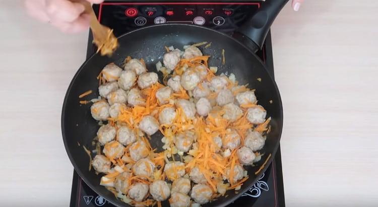 Add chopped carrots and onions to the meatballs in the pan.