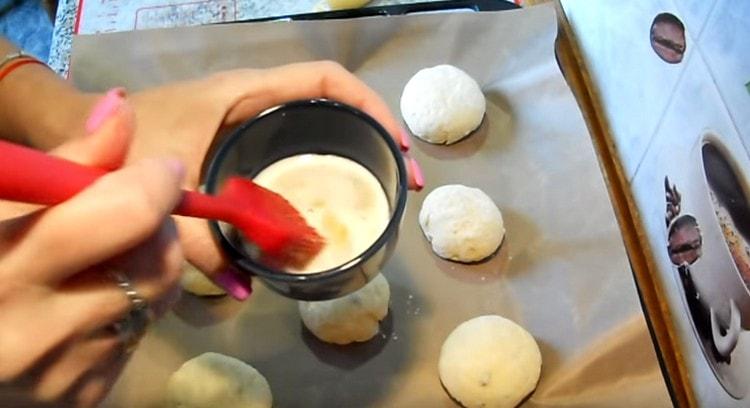 On étale les petits pains sur une plaque à pâtisserie et on les graisse avec un mélange d'œufs et de lait.