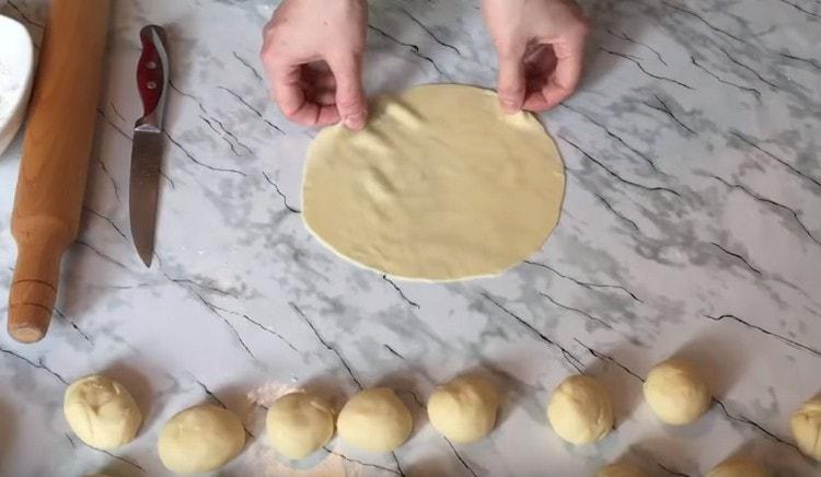 We roll each piece of dough into a thin cake.