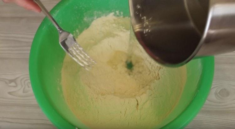 Entrez l'eau bouillante dans la farine en mélangeant la pâte.