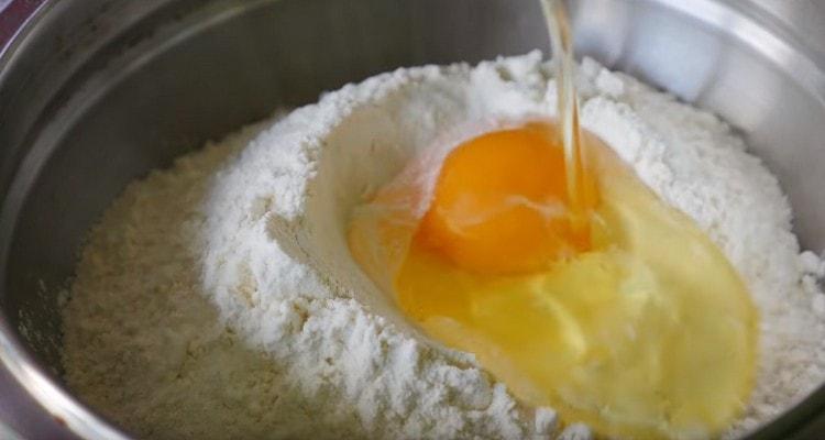 We make a depression in the flour and beat the egg there.