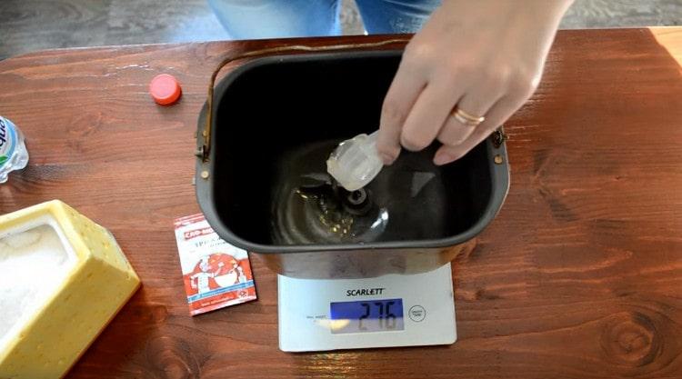 Pour water into a bucket of a bread machine, add salt and vegetable oil.