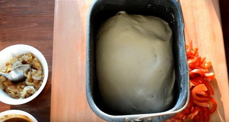 The pizza dough in the bread maker is cooked for an hour and a half.