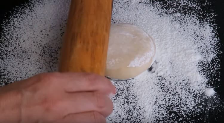 saupoudrer d'un mélange de farine et d'amidon une surface de travail et commencer à étaler la pâte.